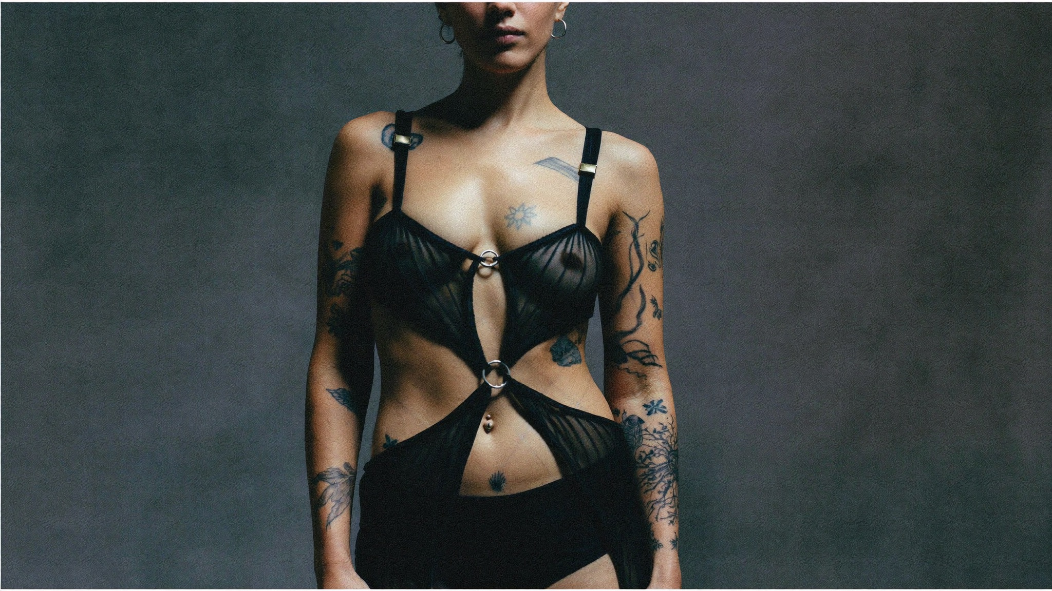 Black mesh top, tattoos reading through, ring hardware
