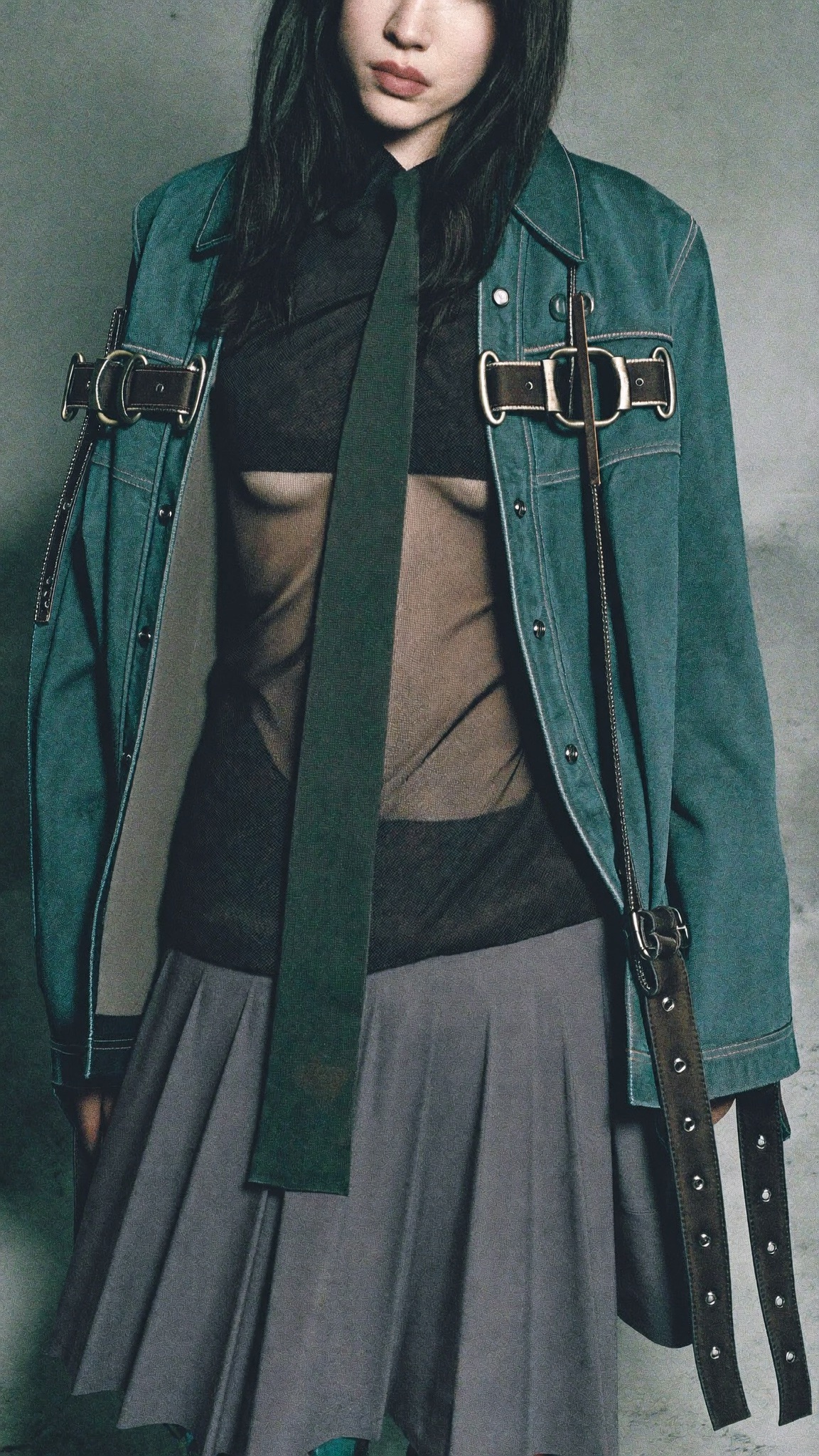 Sheer top, long tie, buckled military jacket, pleated skirt